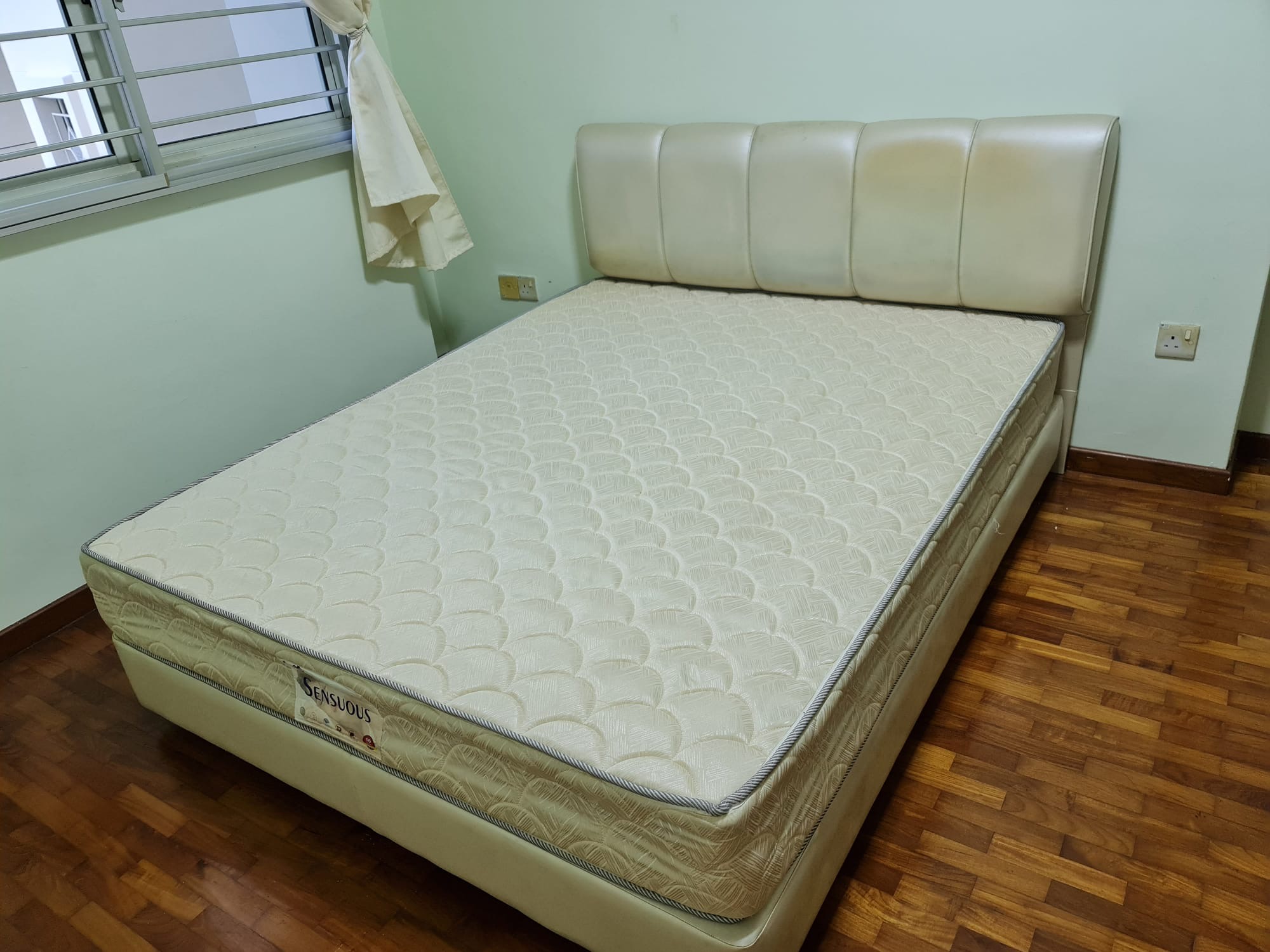 A used queen-size mattress on its base in an HDB bedroom — exactly the kind of bulky piece that's awkward to move down the lift on your own.