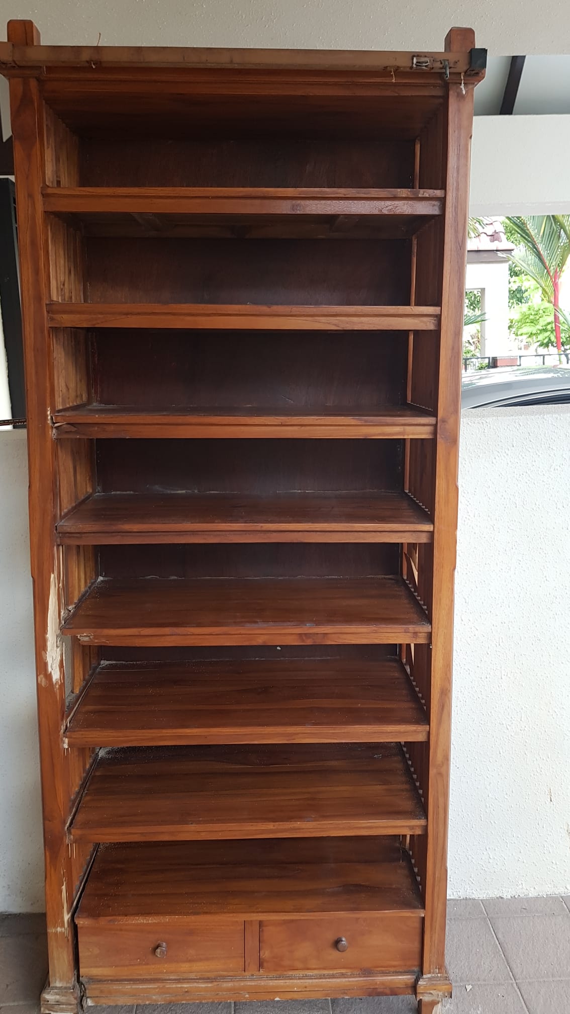 Wooden bookshelf with multiple shelves indoors, ready for disposal.