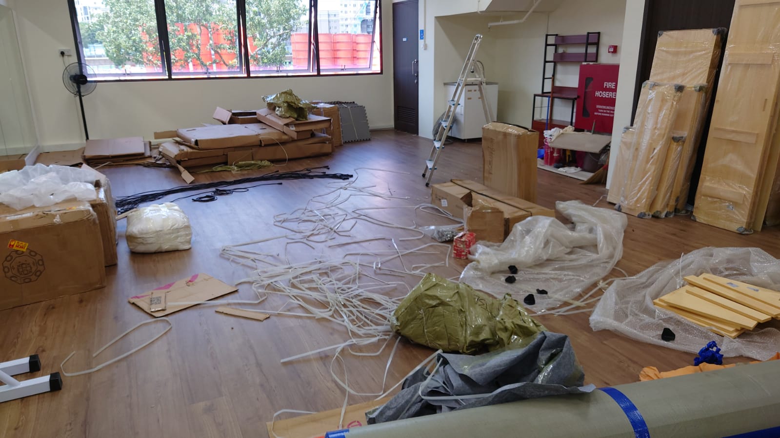 Boxes, packaging materials, and cables scattered on the floor in a room, suggesting a recent clearance or move.