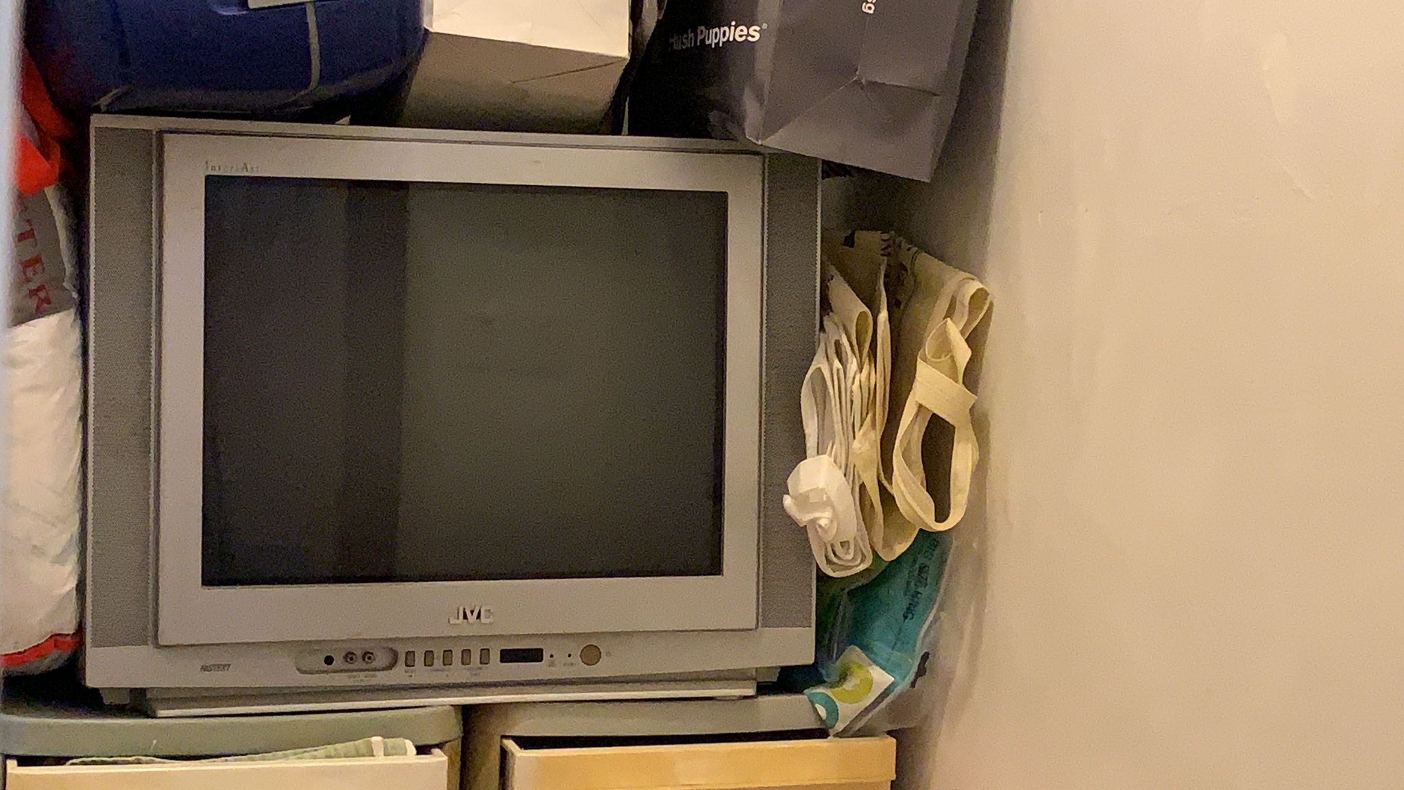 Vintage JVC CRT television surrounded by household items and bags ready for disposal.
