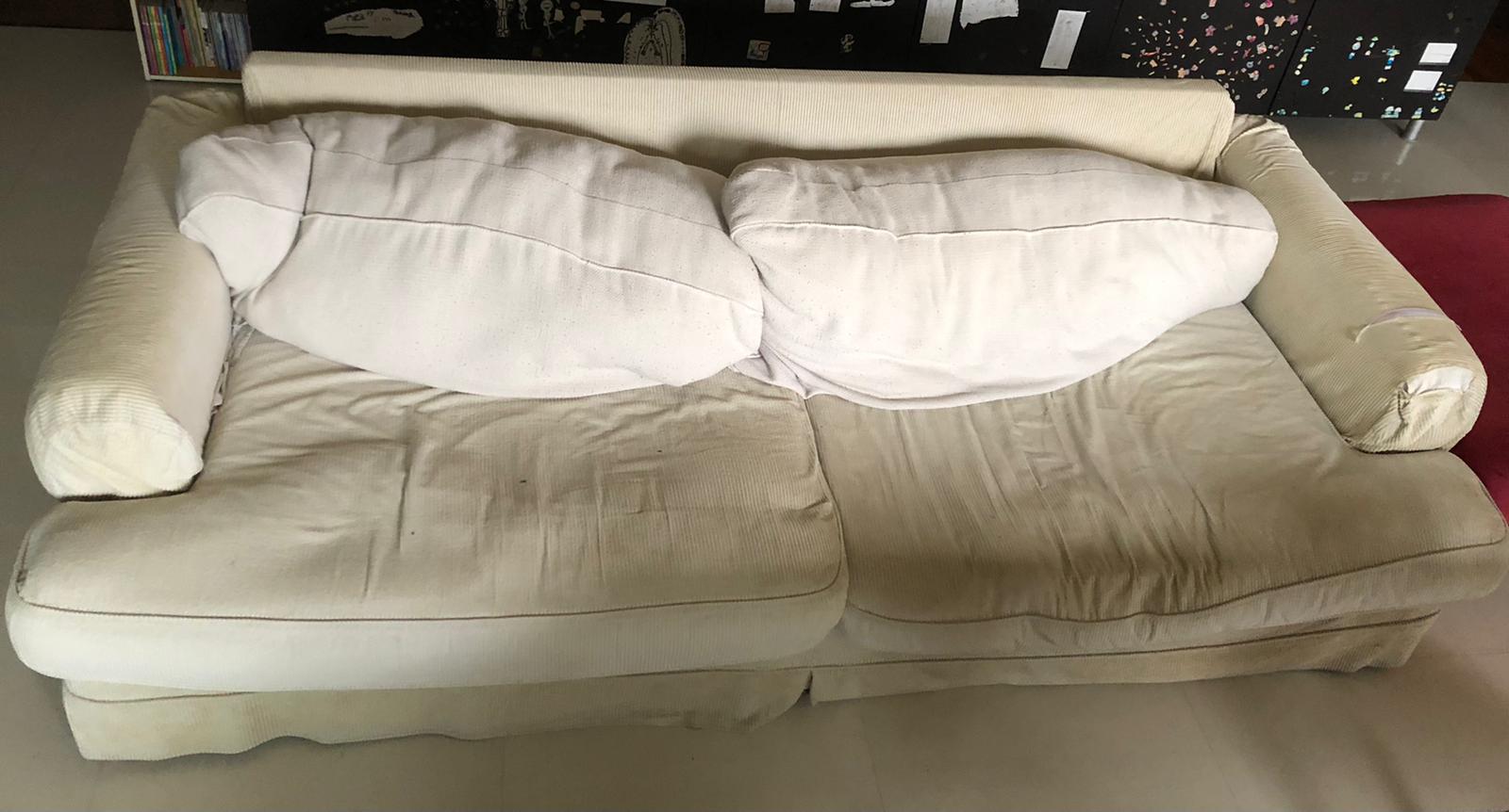 Cream-coloured two-seater sofa with white cushions on a residential floor, ready for collection.