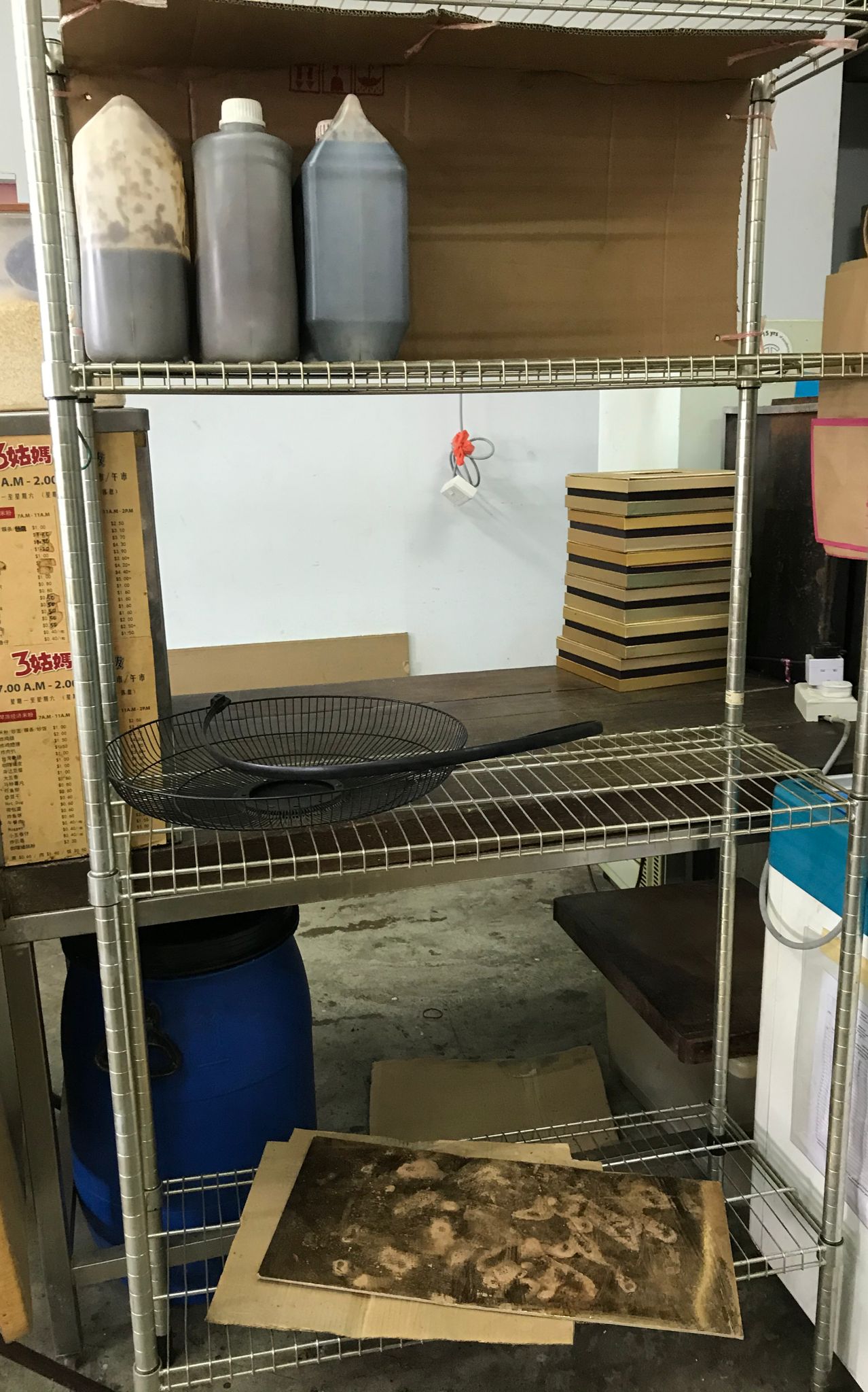Large plastic bins and a mesh storage basket stacked on an industrial metal shelving unit.