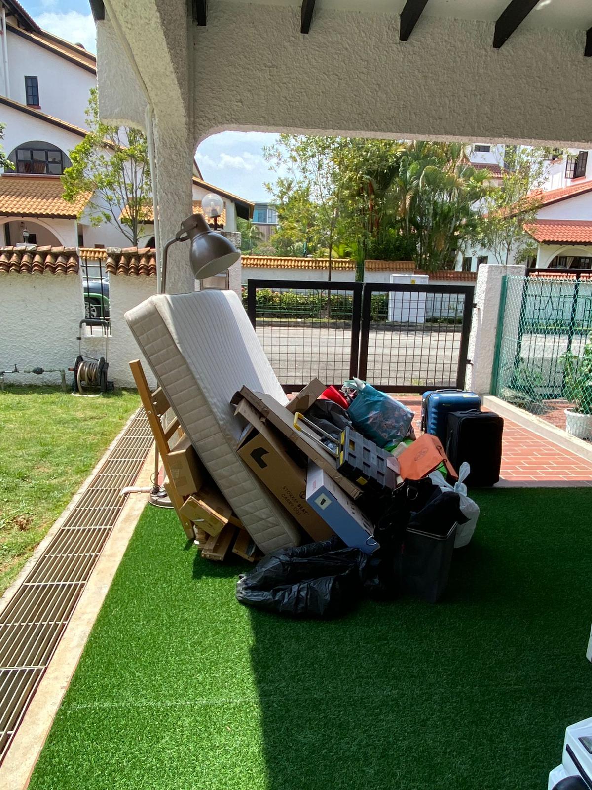 Discarded mattress, wooden furniture pieces, and sealed trash bags piled on artificial turf during a residential junk removal.