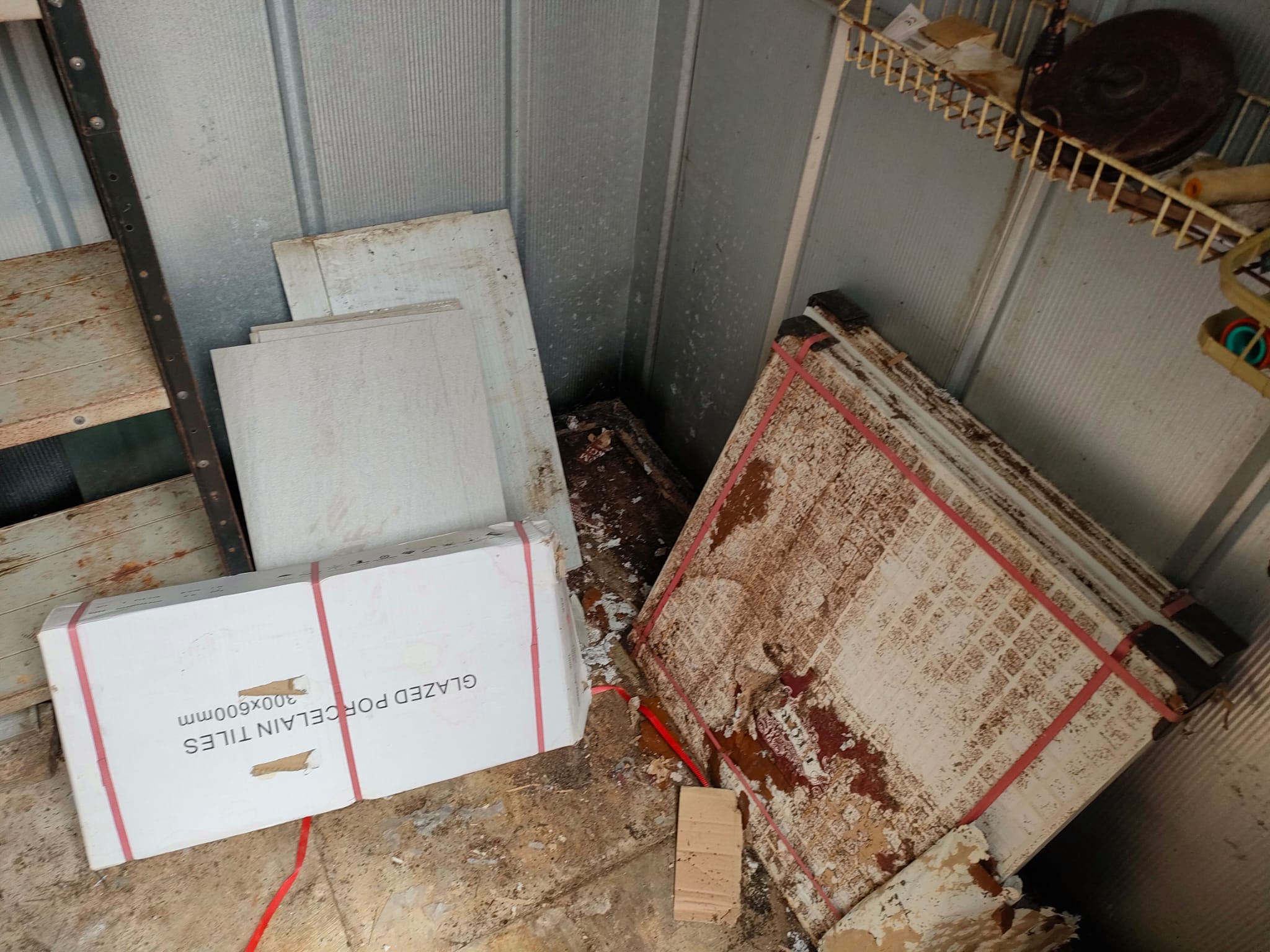 Boxed glazed porcelain tiles next to a torn sack of hacked tile rubble — the typical mix of clean cut-offs and broken pieces that comes out of a kitchen or bathroom retile.