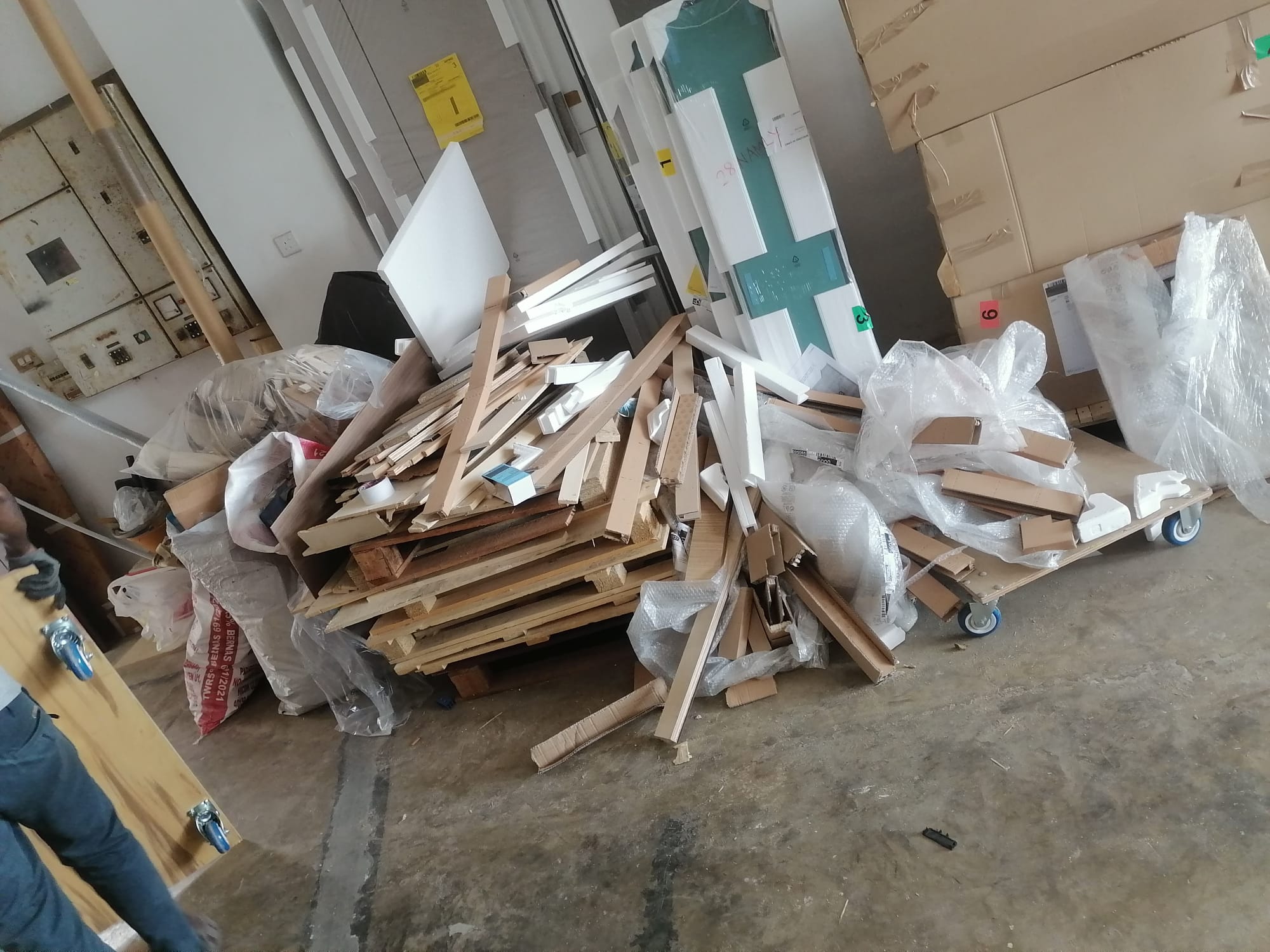 Pile of timber offcuts, drywall scraps, and packaging from a renovation site — exactly the kind of light-to-medium debris that builds up in the corner of a flat by the end of the hacking phase.