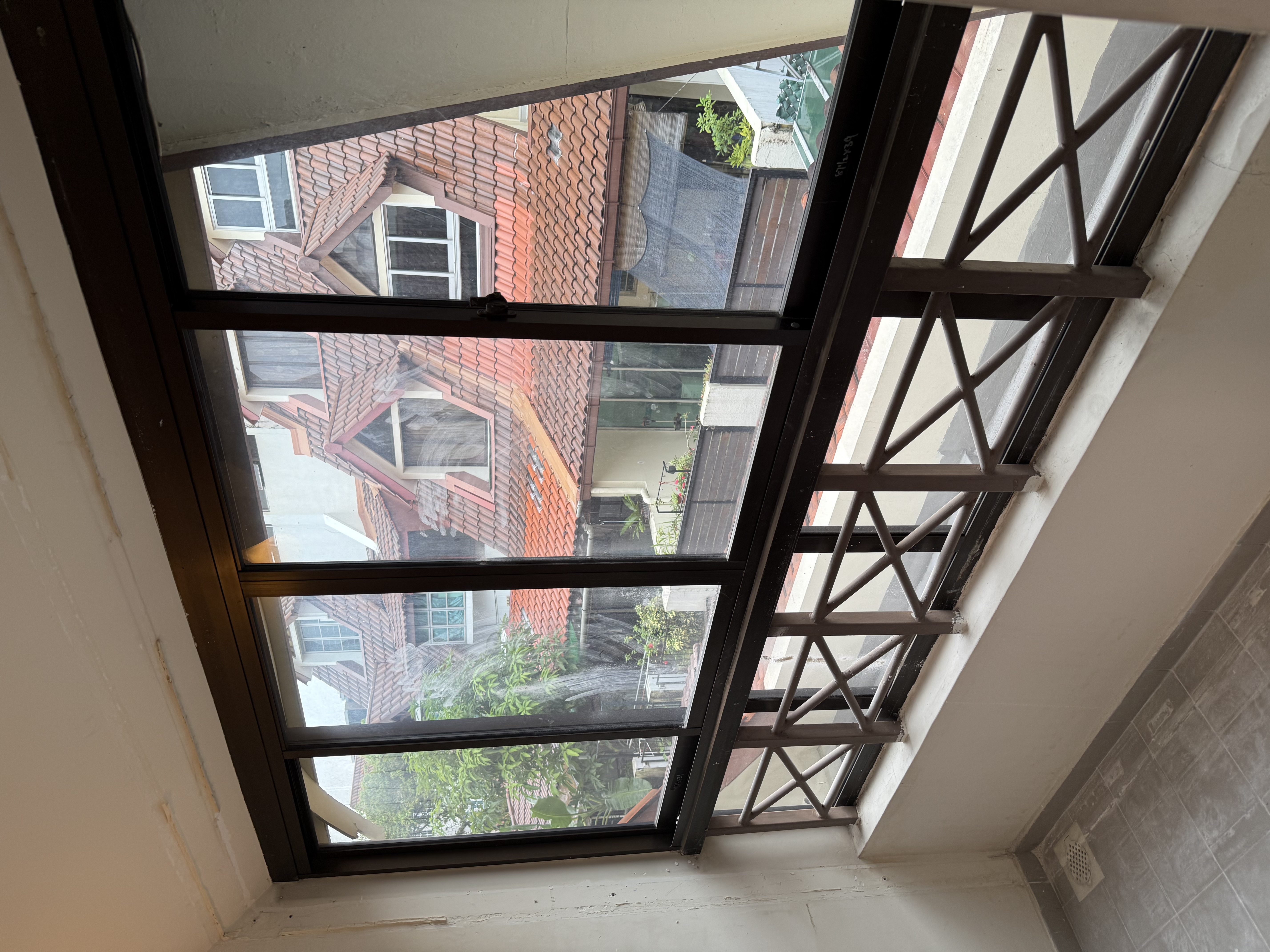 Cleared room in the Pasir Panjang unit after partition wall removal, with the full window line now visible and the space ready for re-tiling.