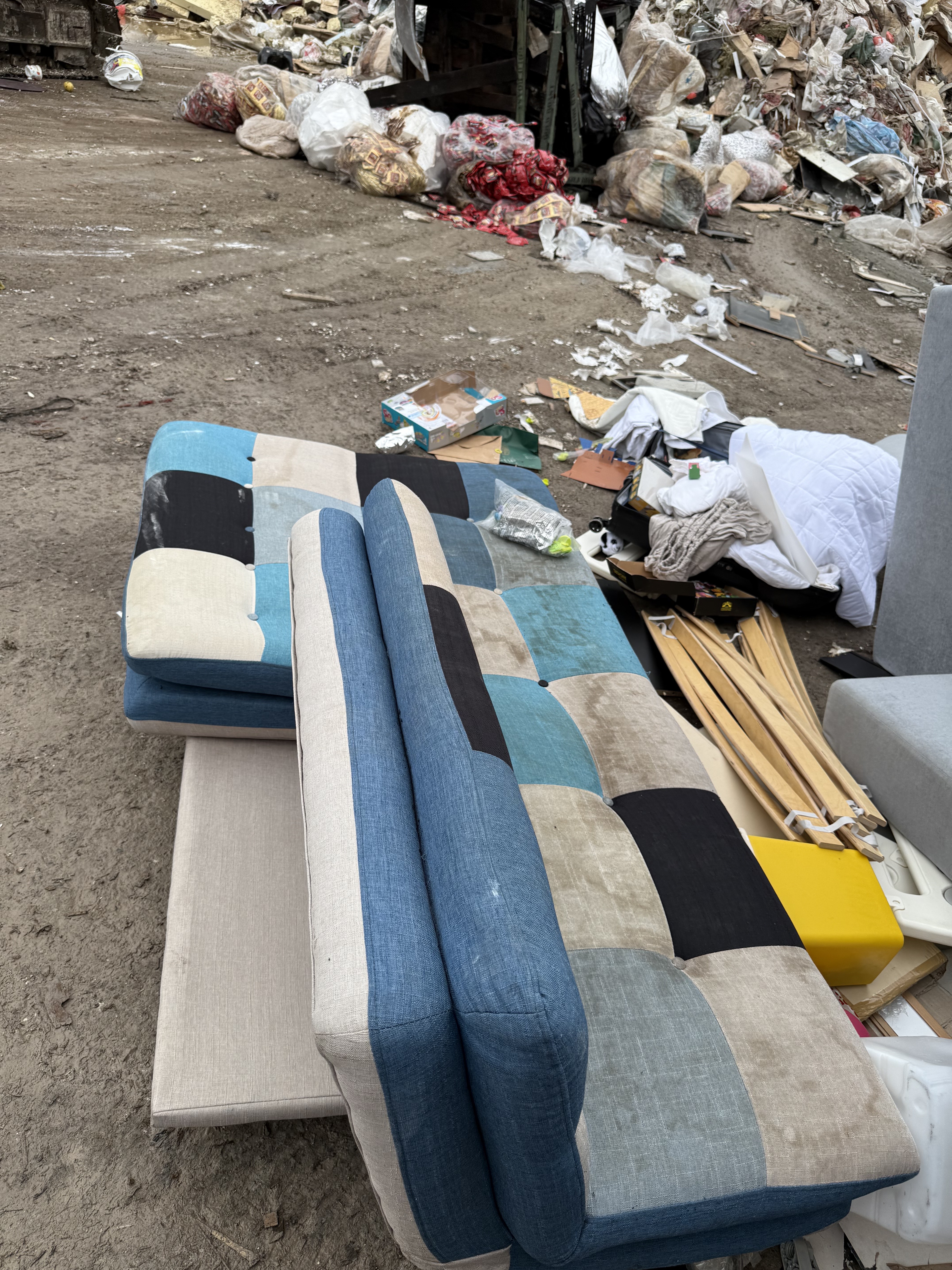 The patchwork sofa bed from the Queenstown pickup, set down at the sorting yard amongst the day's other loads.