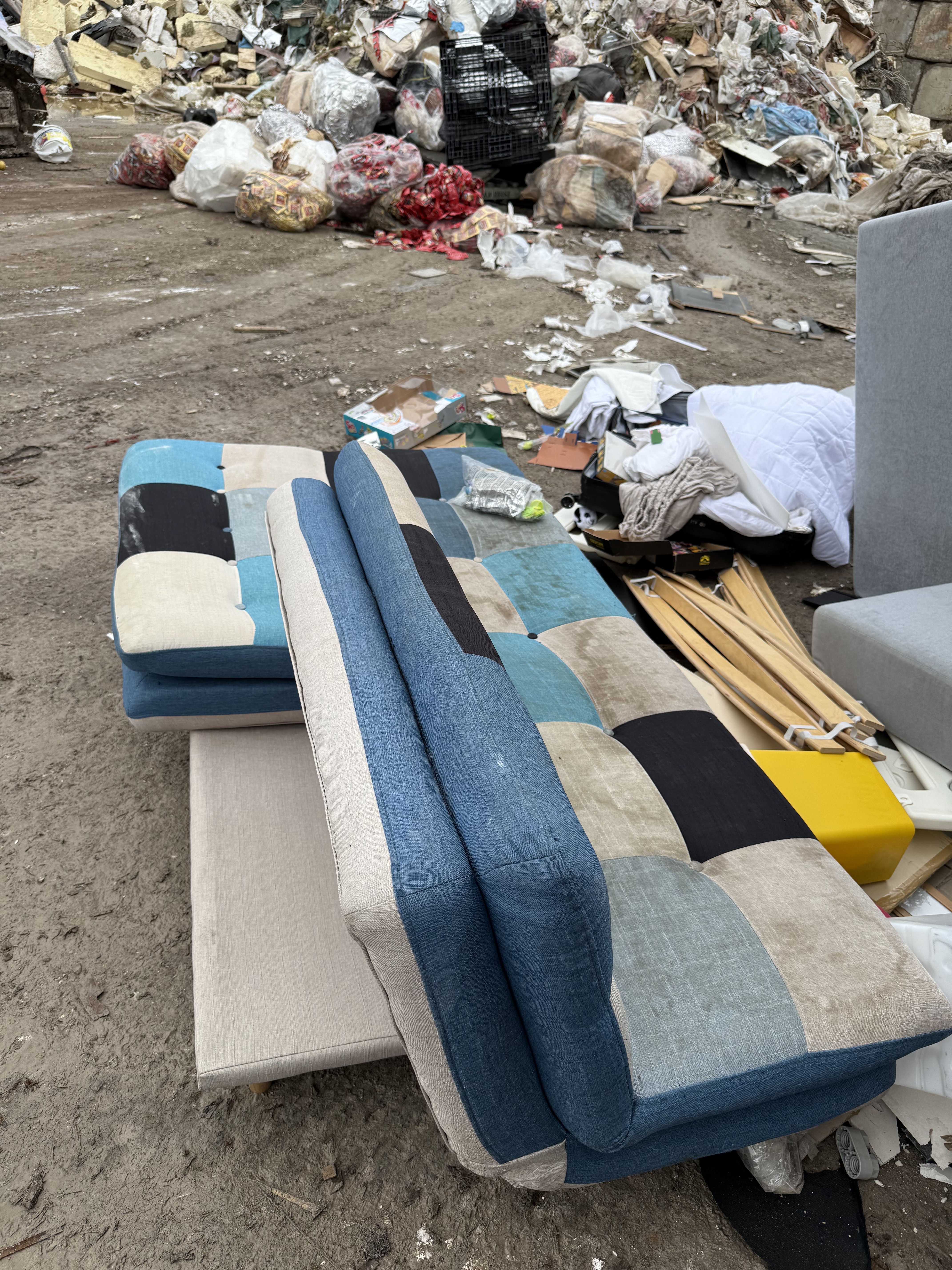Sofa bed cushions stacked at the yard before sorting — the same patchwork pieces that came off the Commonwealth Avenue pickup.
