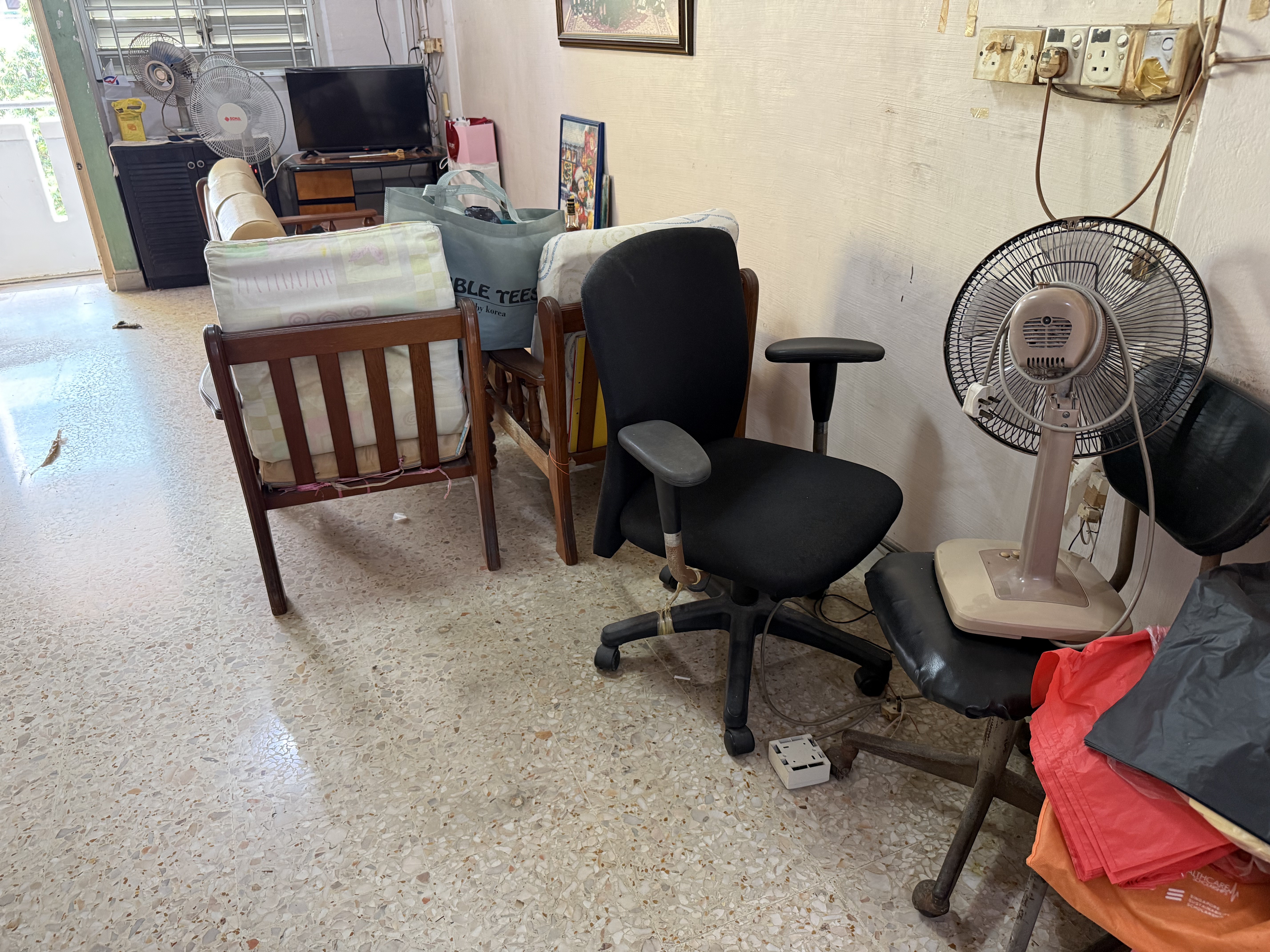 Mixed bulky pile inside an HDB unit — chairs, an old office chair, a fan, drawer panels — the kind of multi-item load we shuttle through the lift in one booked job rather than letting it stage at the void deck.
